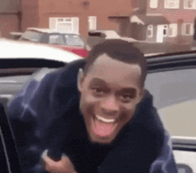 a man is sticking his tongue out while sitting in the back seat of a car .