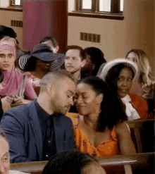 a group of people are sitting in a church and a man and woman are looking at each other .