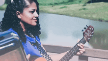 a woman in a blue shirt is holding a guitar with the brand name taylor on it