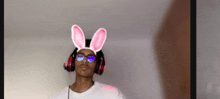 a man wearing bunny ears and headphones is standing in front of a white wall .