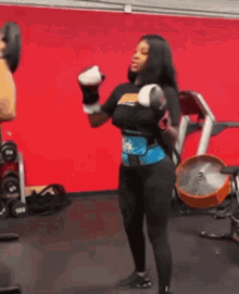 a woman is wearing boxing gloves and a belt in a gym .