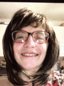 a woman with glasses and a wig smiles for the camera