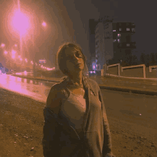 a woman is standing on a street at night