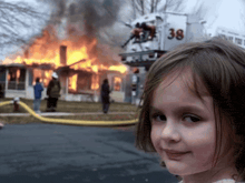 a little girl stands in front of a burning house and a fire truck with the number 38 on it