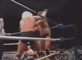 two men are boxing in a ring with a referee in the background .