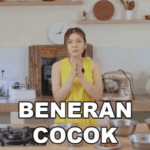 a woman in a yellow tank top stands in front of a kitchen counter with the words beneran cocok written on it