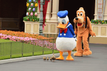 donald duck and pluto are walking with ducklings on the street