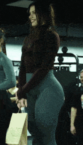 a woman standing in a gym with a bag in her hand