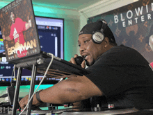 a man wearing headphones sits in front of a laptop that says blowin ' entertaiment