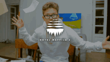 a boy wearing glasses and a white sweatshirt that says hotel maffija 2 on it