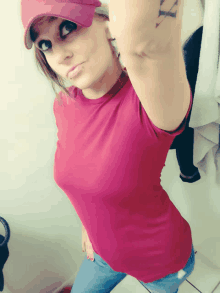 a woman wearing a red shirt and a red hat has a tattoo on her arm