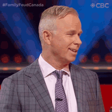 a man in a suit and tie stands in front of a blue background with the letters cbc on it