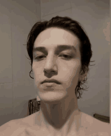 a young man without a shirt is taking a selfie in a bathroom