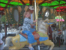 a little girl is riding a carousel with a man holding her