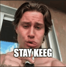 a man without a shirt is making a funny face with the words stay keeg on his face .