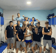 a group of young men posing for a picture in a locker room with one wearing a shirt that says " just do it "