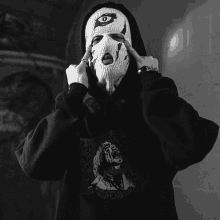 a black and white photo of a person wearing a ski mask and hoodie