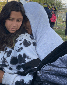 a girl in a black and white tie dye sweatshirt is hugging a man in a grey hoodie