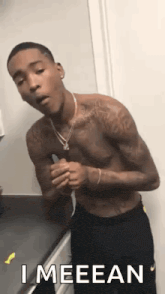 a shirtless man is standing in a bathroom with a knife in his hand and a necklace around his neck .