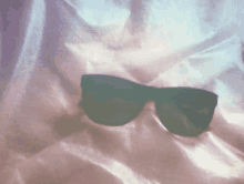 a pair of sunglasses is laying on a purple cloth