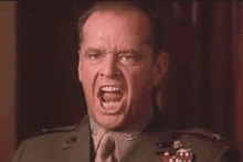 a close up of a man in a military uniform screaming with his mouth open .