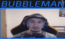 a man wearing headphones is sitting in front of a microphone with the name bubbleman written above him