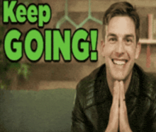 a man is smiling in front of a sign that says " keep going "