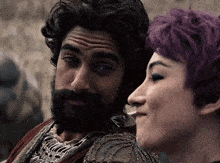 a man with a beard and a woman with purple hair looking at each other