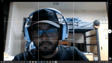 a man wearing headphones and glasses takes a picture of himself on a computer screen