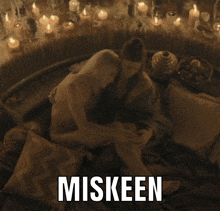 a couple laying on a bed with candles behind them and the word miskeen above them