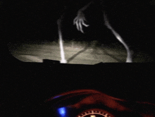 a blurred image of a person driving a car at night with a hand reaching out