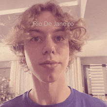 a young man with curly hair is wearing a blue shirt with the words rio de janeiro written on it