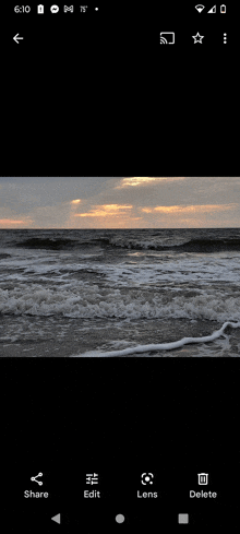 a phone screen shows a picture of a beach with waves coming in