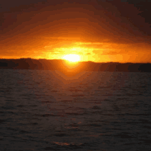 a sunset over a body of water with mountains in the distance