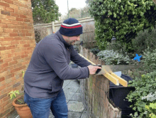 a man wearing a blue and red hat is cutting a piece of wood