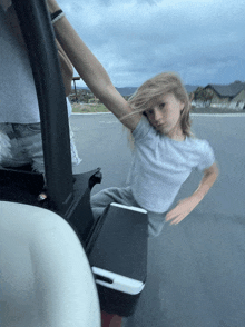 a young girl is riding in a golf cart with a cooler in the back