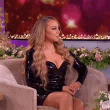 mariah carey is sitting in a chair wearing a black dress and a necklace .