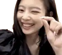 a woman with long black hair is smiling and holding her finger to her face .