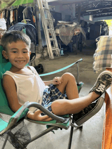 a young boy is sitting in a chair with his feet up and smiling