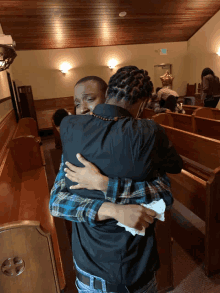 a man in a black shirt is hugging a woman in a plaid shirt