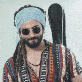 a man with dreadlocks and sunglasses is wearing a headband .