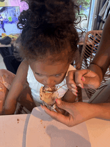 a little girl eating ice cream from a cone with a spoon