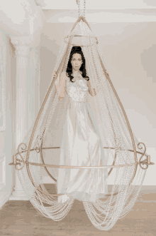 a woman in a long dress is hanging from a chandelier