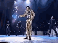 a man in a gold suit is dancing on a stage in front of a group of people .