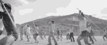 a black and white photo of a group of people holding sticks in front of a hill with the letter l on it ..