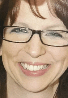 a close up of a woman wearing glasses smiling for the camera