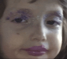 a close up of a child 's face with purple makeup on