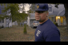 a man standing in front of a house wearing a hat and a t-shirt that says " tomorrow we will be free "