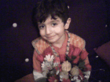 a young boy wearing a red and orange shirt with flowers on it