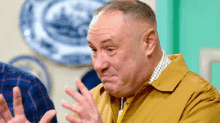 a man in a yellow jacket is making a funny face with his hands